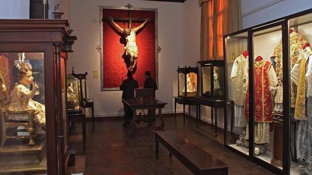 Una de las salas, con vestimentas litúrgicas del XVIII, Niños Jesús y el Cristo del Capítulo, crucificado dieciochesco de papel recién restaurado